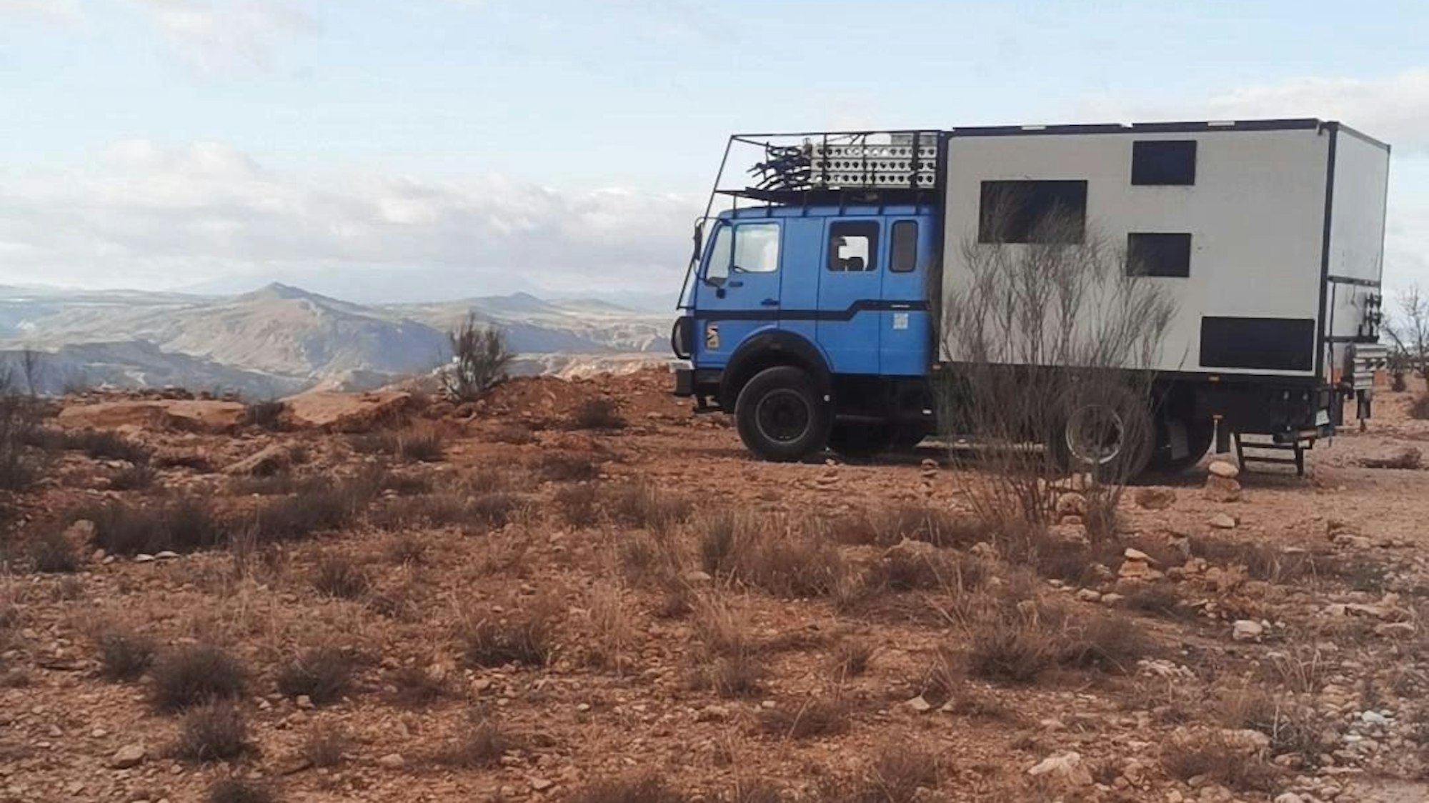 Ein blaues Expeditionsmobil in einer Landschaft.