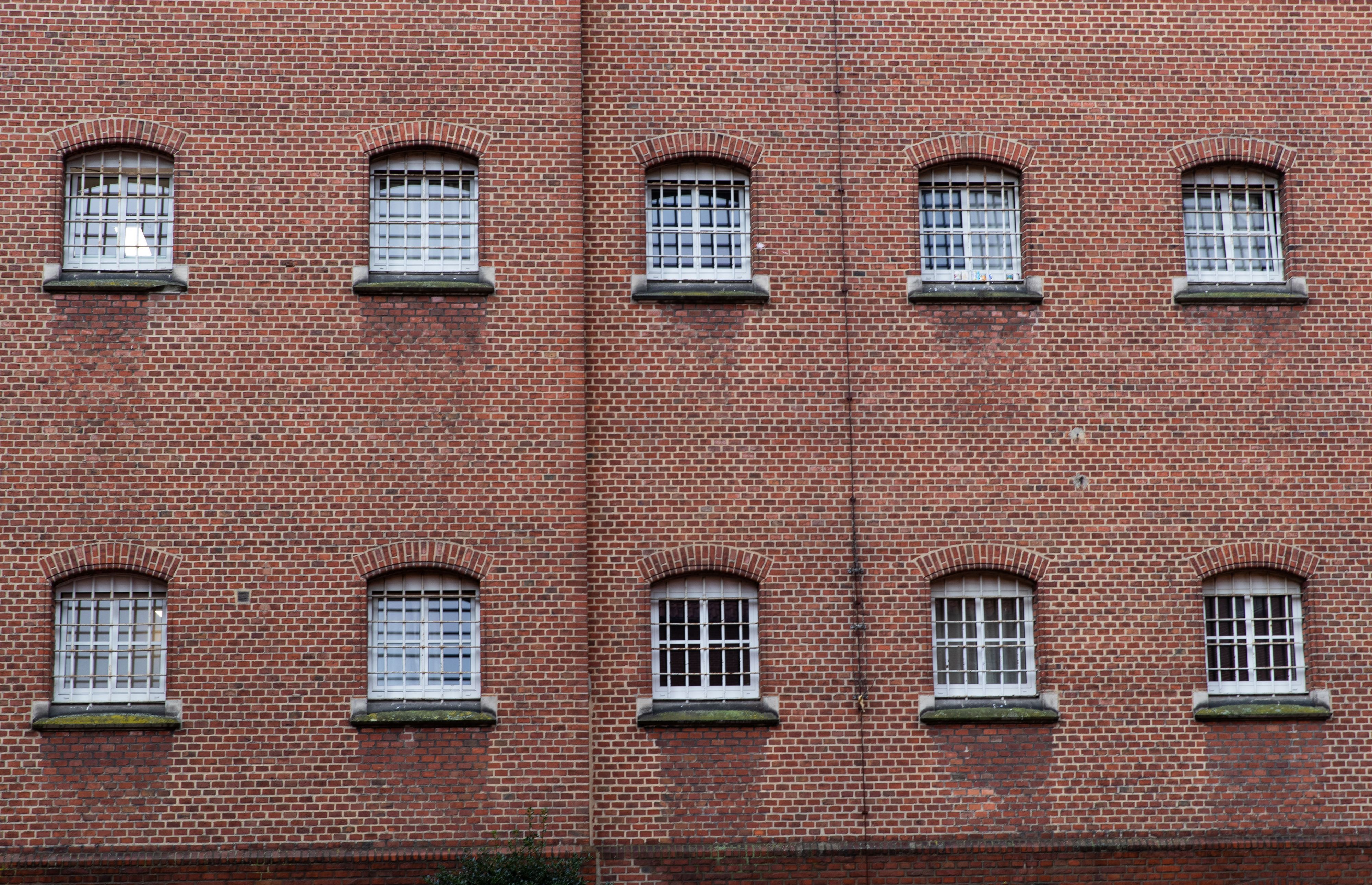 Vergitterte Fenster prägen die Fassade einer JVA. (Symbolbild)
