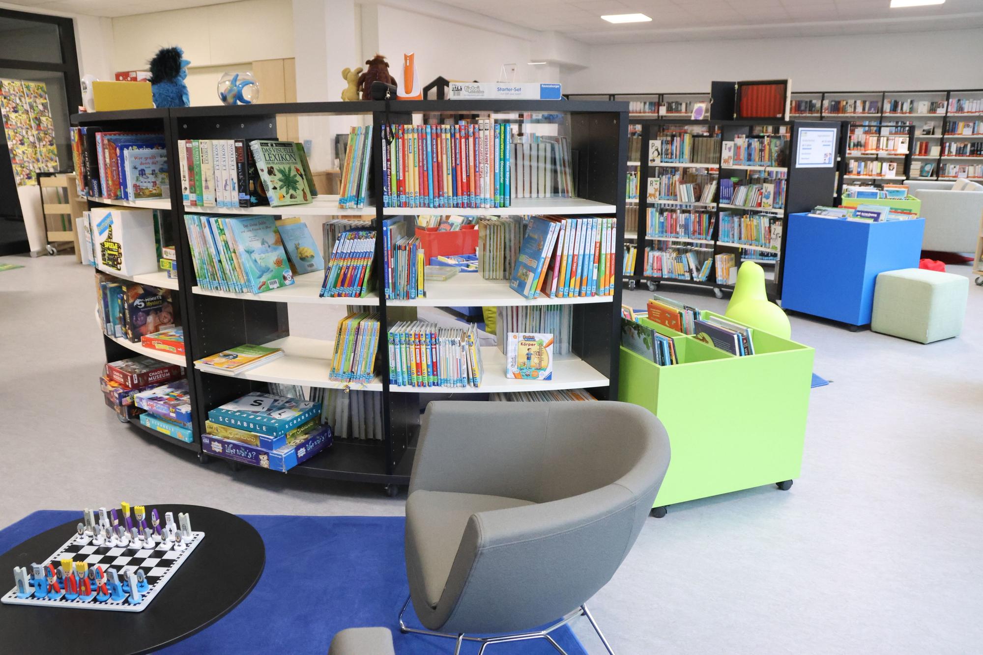 Bücherregale, Sessel und ein kleiner Tisch mit einem aufgebauten Schachspiel.