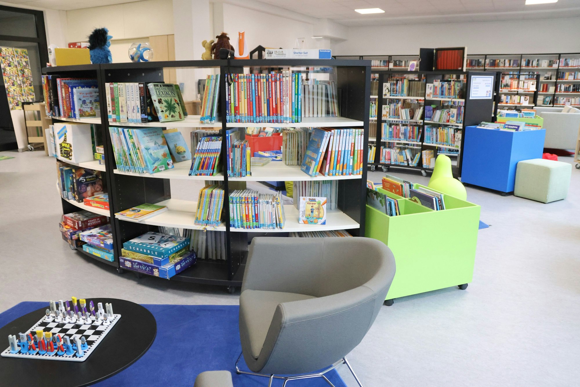 Bücherregale, Sessel und ein kleiner Tisch mit einem aufgebauten Schachspiel.