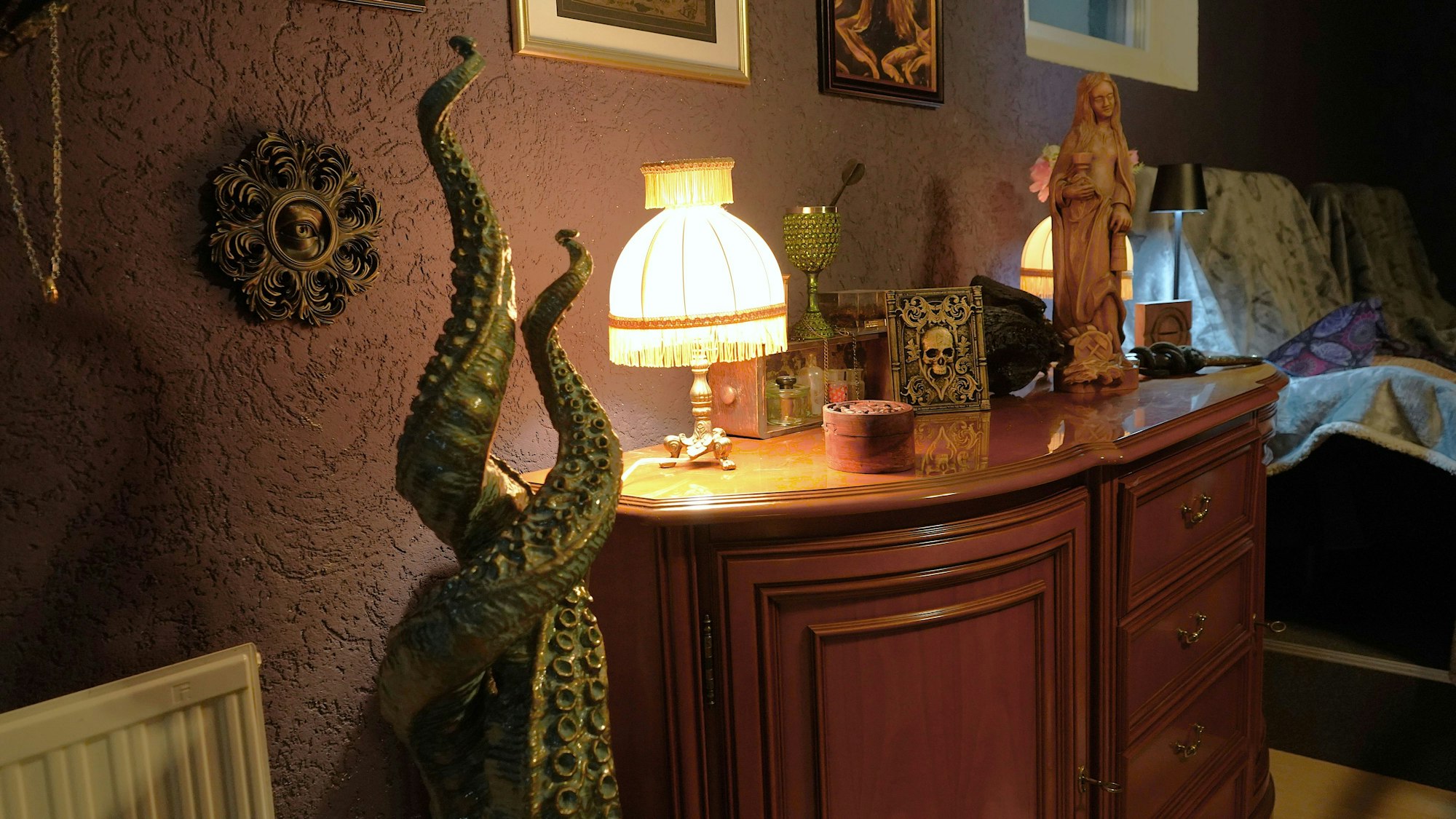 Das Foto zeigt eine Kommode mit einer älteren Lampe und zahlreichen Deko-Objekten.