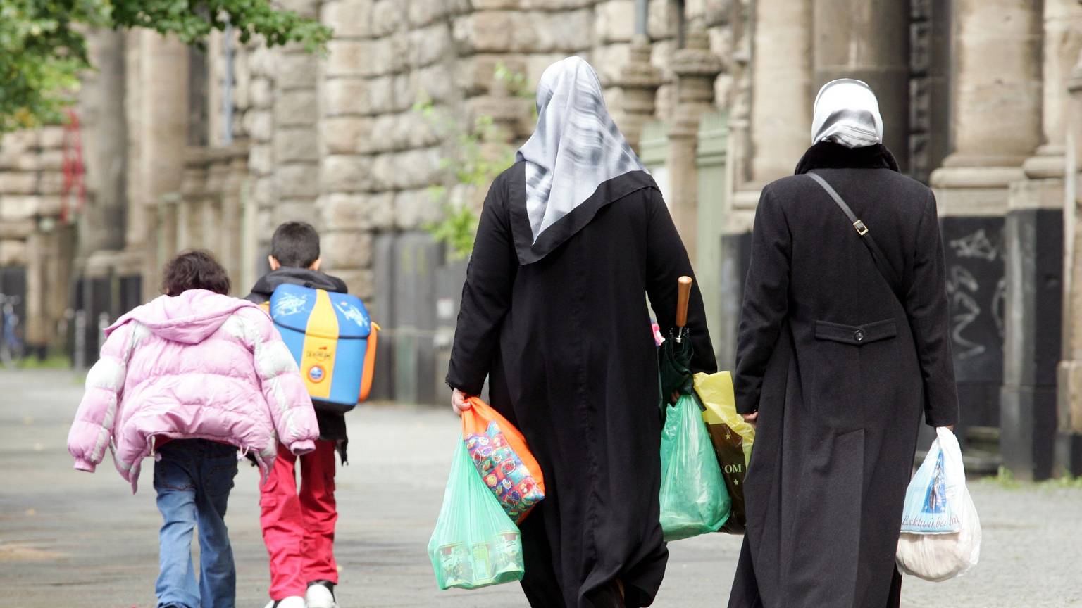 ARCHIV - Türkische Frauen mit Kopftüchern, Einkaufstaschen und ihren Kindern in Berlin