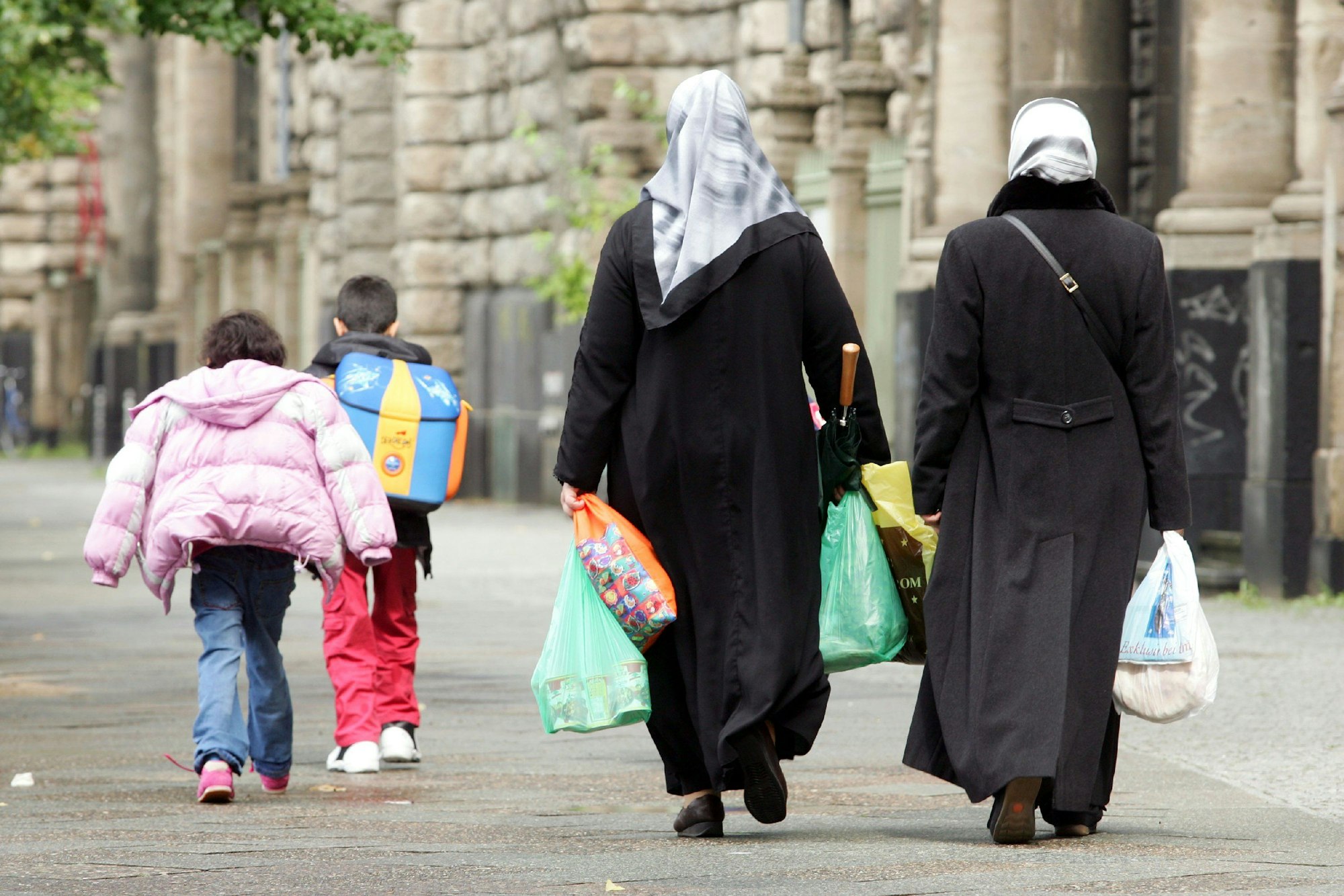 ARCHIV - Türkische Frauen mit Kopftüchern, Einkaufstaschen und ihren Kindern in Berlin