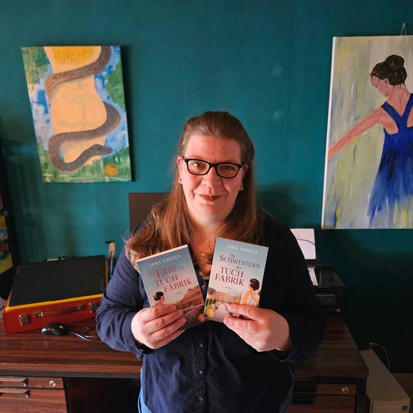 Jana Engel aus Kall steht vor ihrem Schreibtisch und hält die beiden Bücher der Tuchindustrie-Reihe in den Händen.