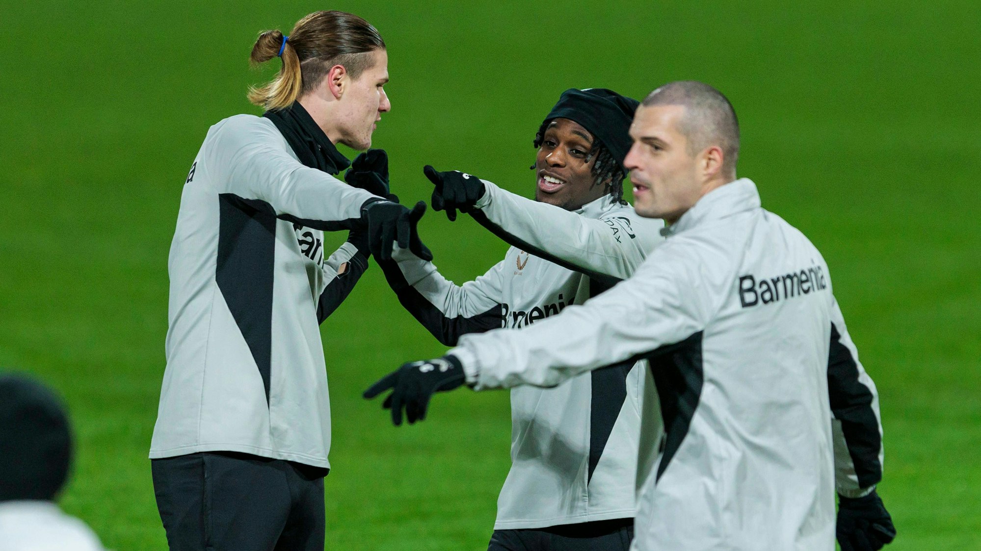 Gut gelaunt und neu frisiert ins neue Jahr: Granit Xhaka (r.) präsentiert sich mit kahl rasiertem Kopf neben seinen Teamkollegen Jeremie Frimpong und Artem Stepanov (l.) beim Trainingsauftakt von Bayer 04 Leverkusen.