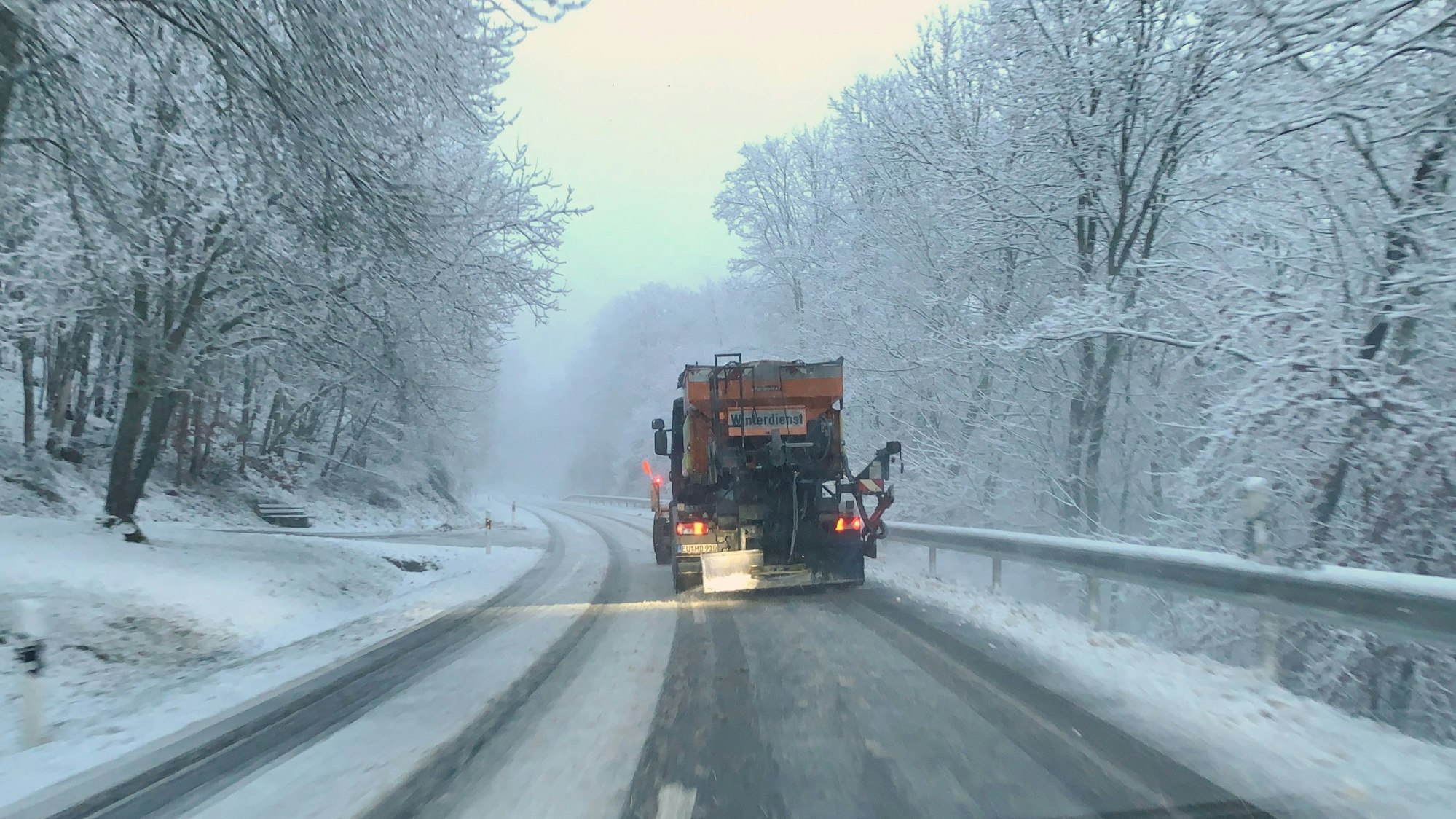 Ein Fahrzeug des Winterdienstes räumt eine verschneite Straße bei Wildenburg im Kreis Euskirchen.