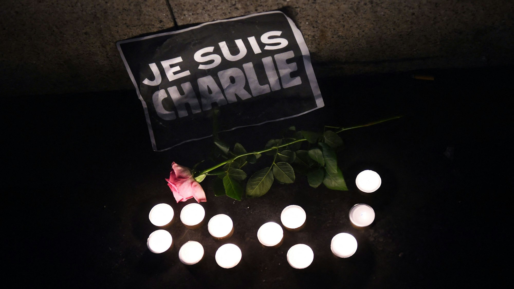 Kerzen, eine Rose und ein Schild, auf dem auf Französisch "Ich bin Charlie" steht, sind nach dem Anschlag auf dem Boden abgelegt worden. (Archivbild)