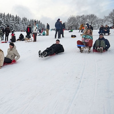 Zahlreiche Rodler fahren den Hang hinab.