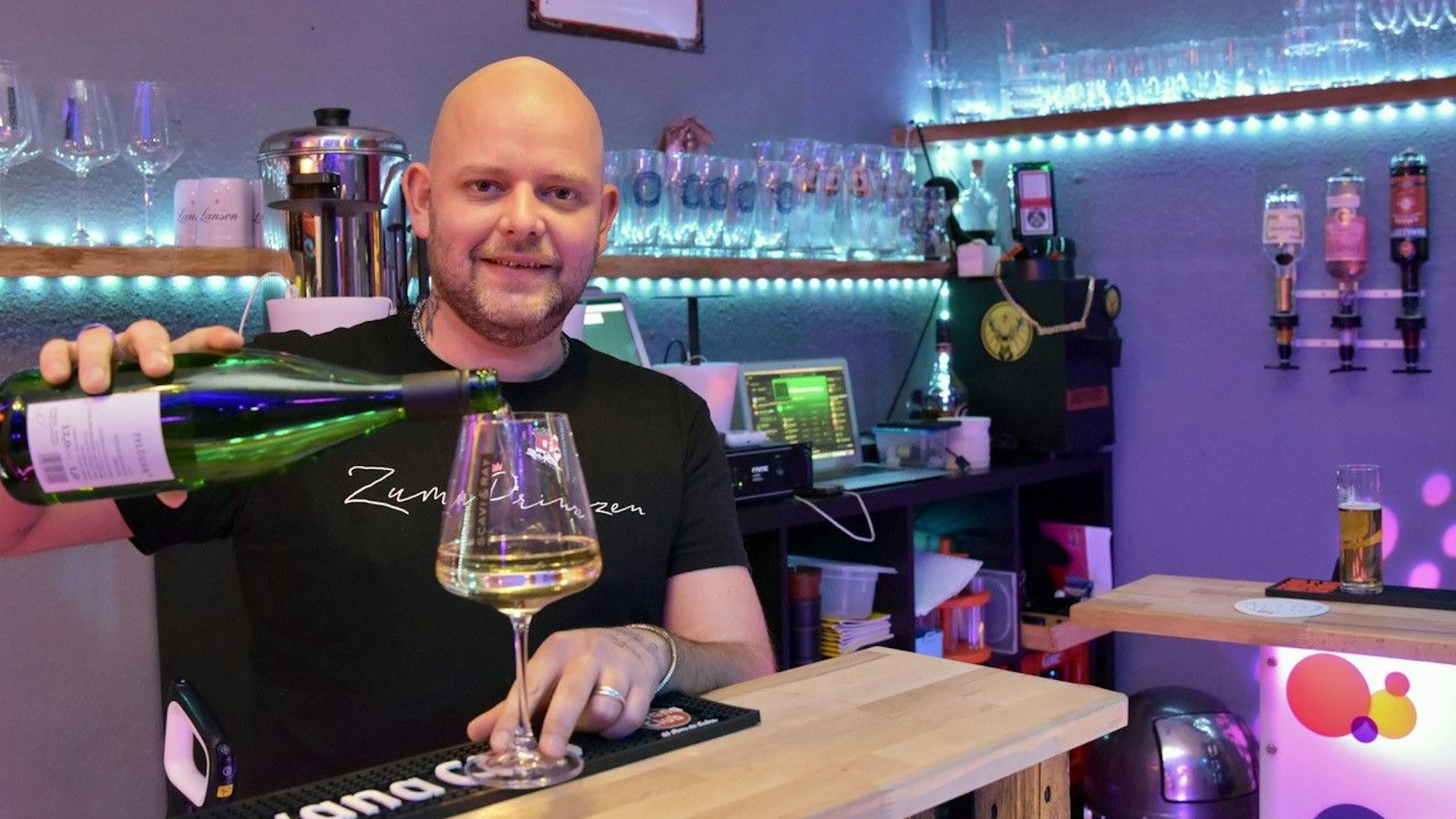 Ein kahlköpfiger Mann schenkt in der Siegburger Kneipe Zum Prinzen ein Glas Weißwein ein.