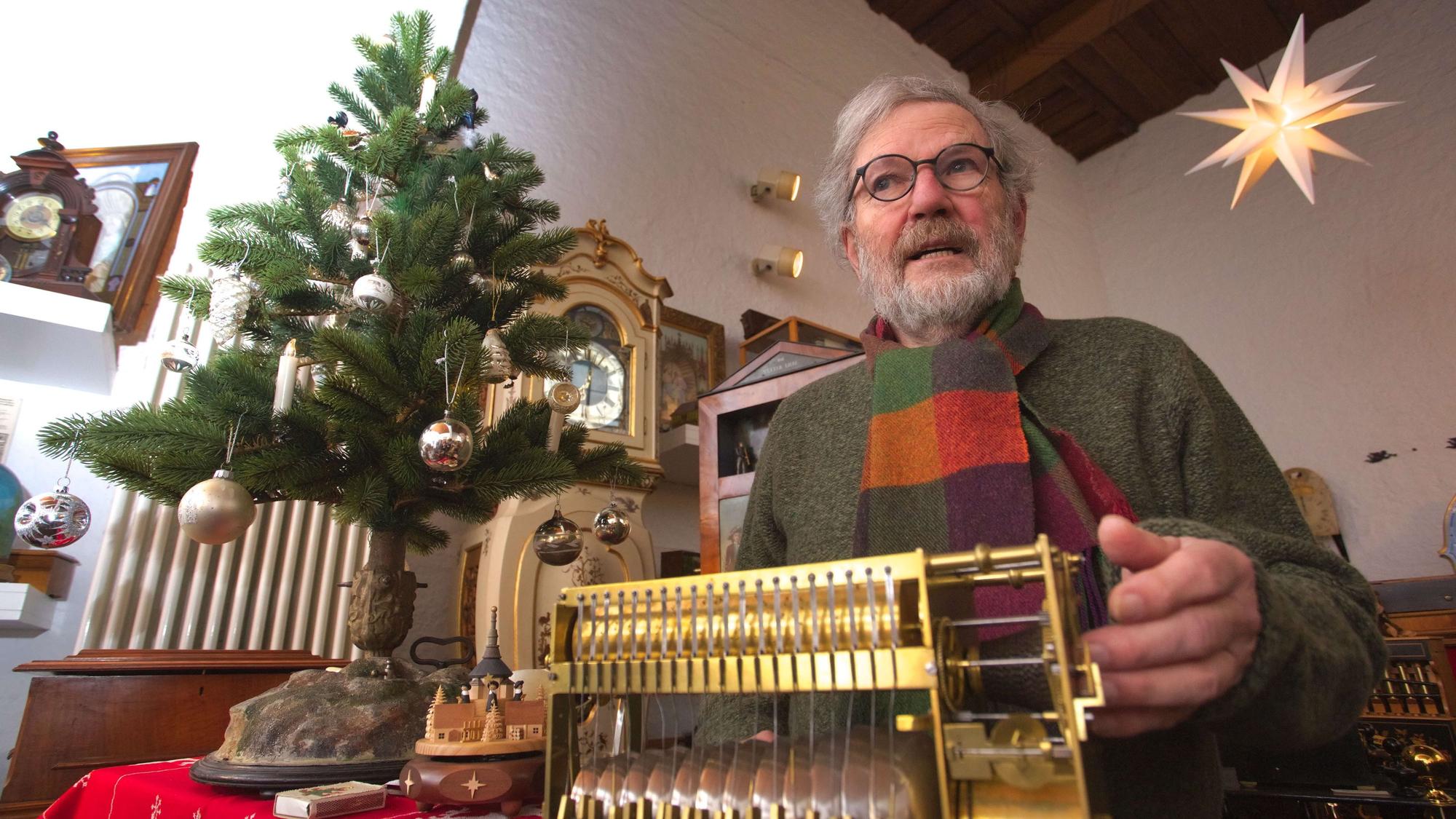 Ullrich Wimmer sitzt hinter einem mechanischen Musikinstrument, eine Hand hat er an der Kurbel.