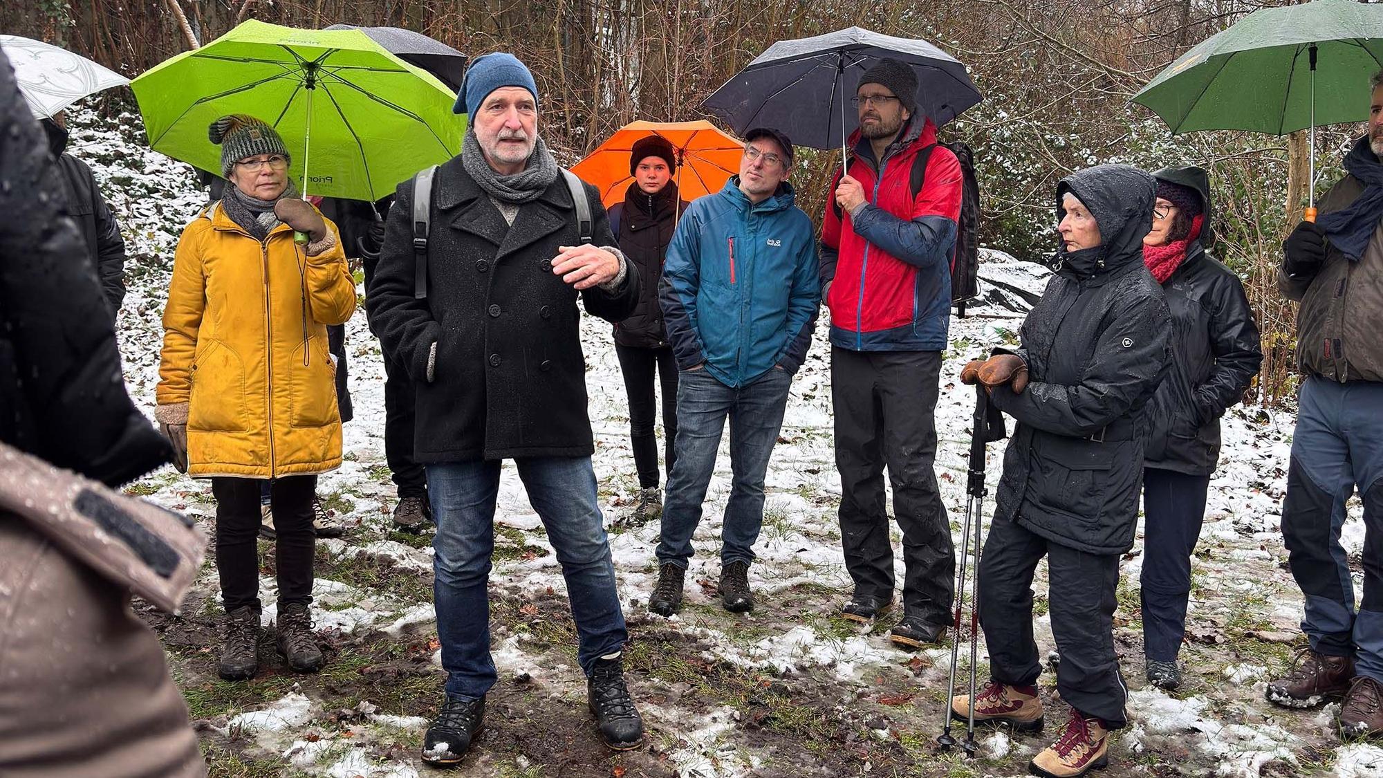Menschen stehen mit Regenschirmen auf einem Feld.