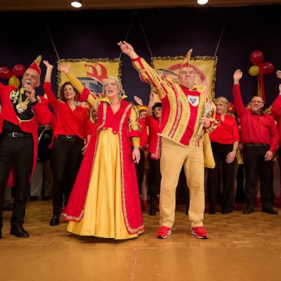 Das Prinzenpaar mit seinem Gefolge jubelt auf der Bühne den Jecken zu.