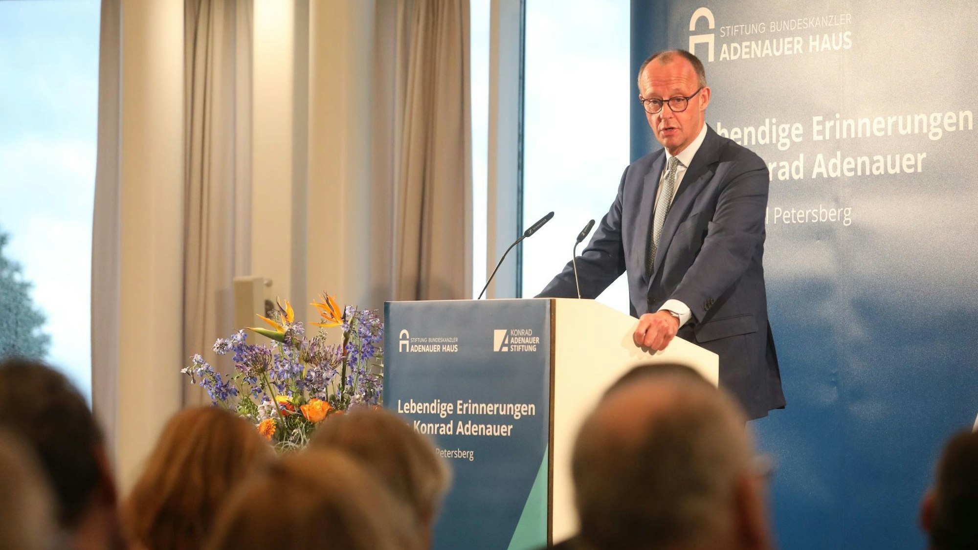 Auf Einladung der Kontrad-Adenauer-Stiftung sprach Friedrich Merz auf dem Petersberg: Ein großer Mann im Anzug steht an einem Rednerpult.