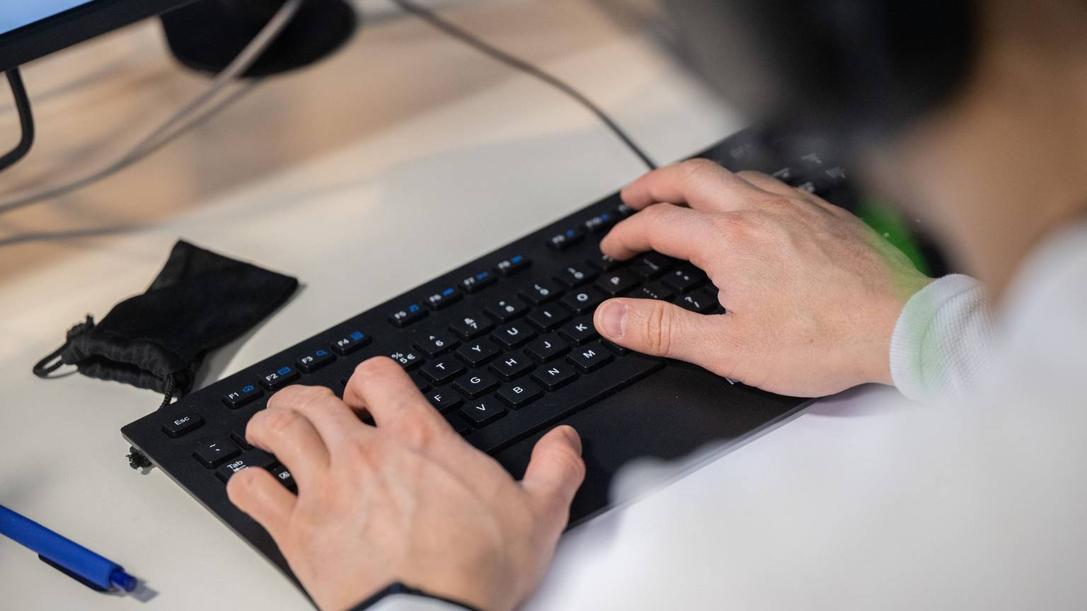 Hände tippen auf einer Computertastatur.