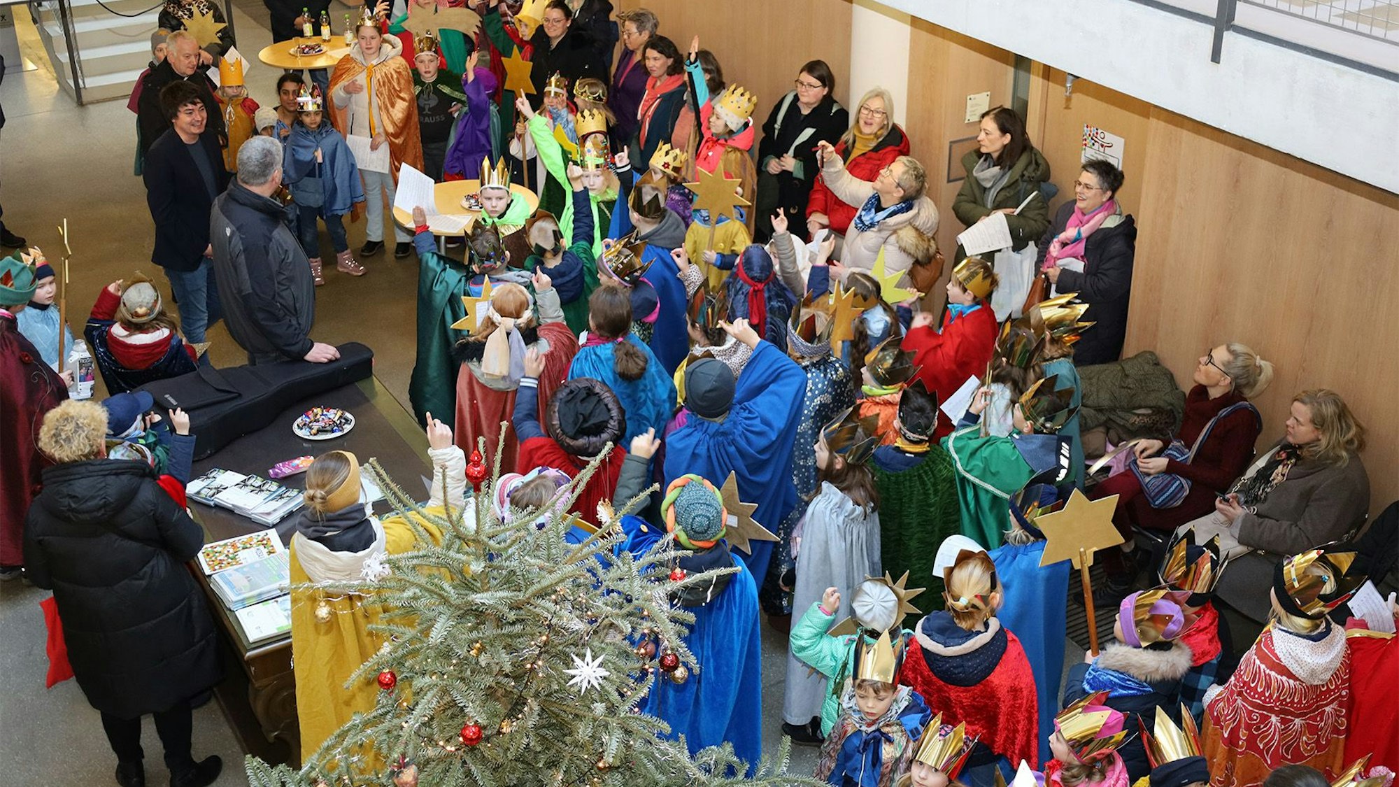 Blick von oben ins Foyer des Hennefer Rathauses, wo die bunt kostümierten Sternsinger versammelt sind.