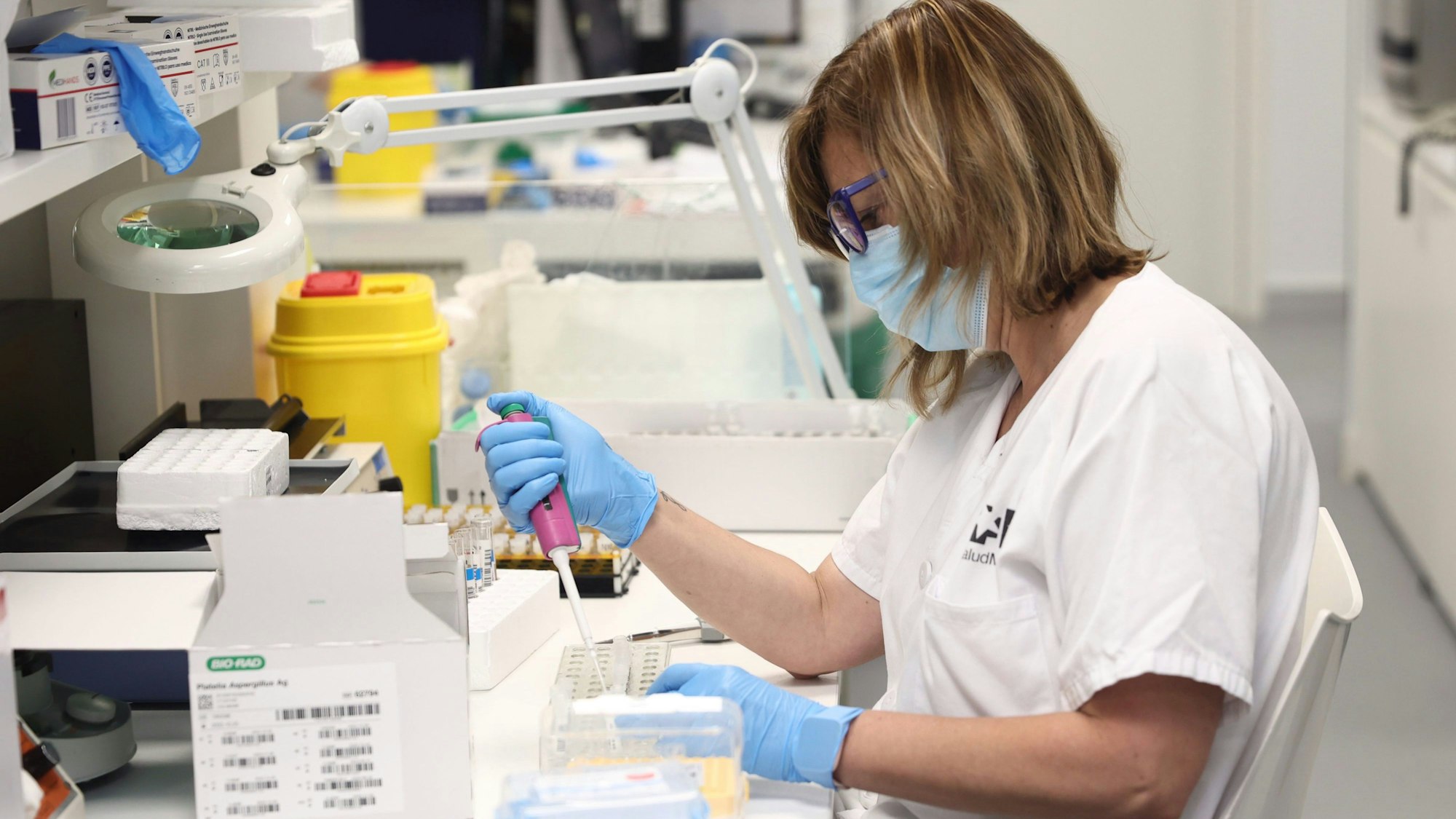 Eine Frau mit Gesichtsmaske arbeitet in einem Labor.
