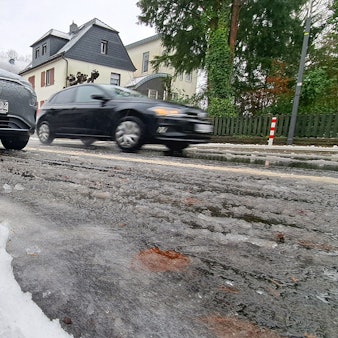 Schneematsch liegt auf der Bensberger Straße in Overath-Heiligenhaus. Autos fahren darüber.
