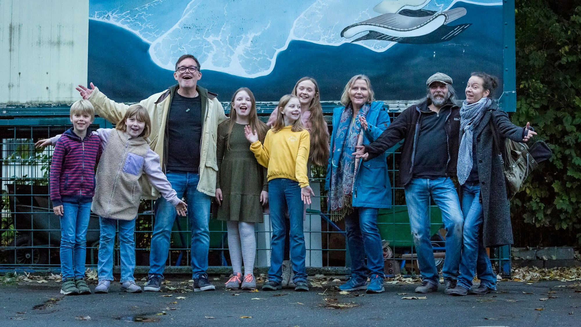 Kinder und Erwachsene lächeln in die Kamera.