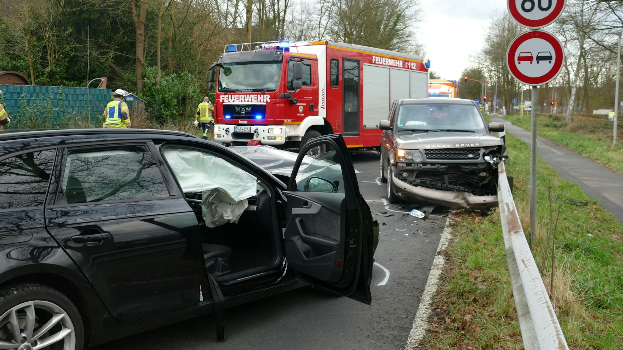 Zwei Fahrzeuge mit deutlichen Unfallspuren stehen auf der Straße, ein Feuerwehrfahrzeug dahinter.