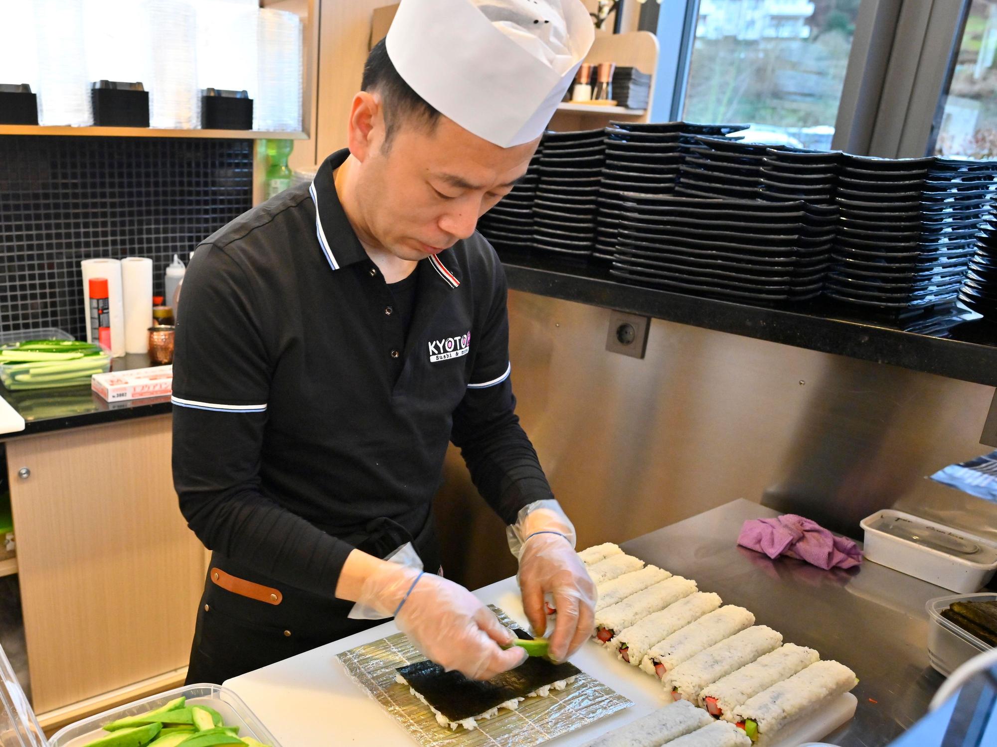Ein Mann bereitet Sushi zu.