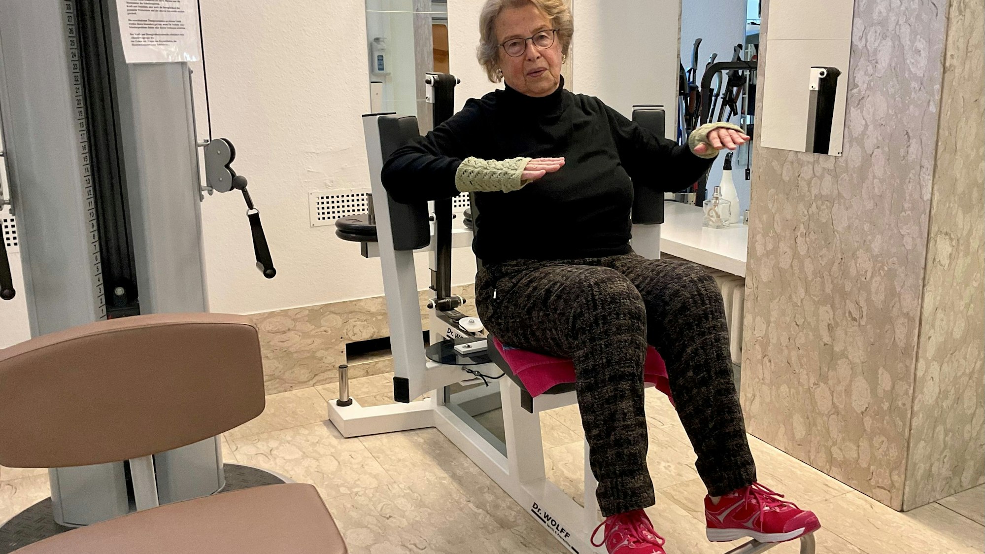 Eine ältere Frau sitzt auf einem Fitnessgerät.