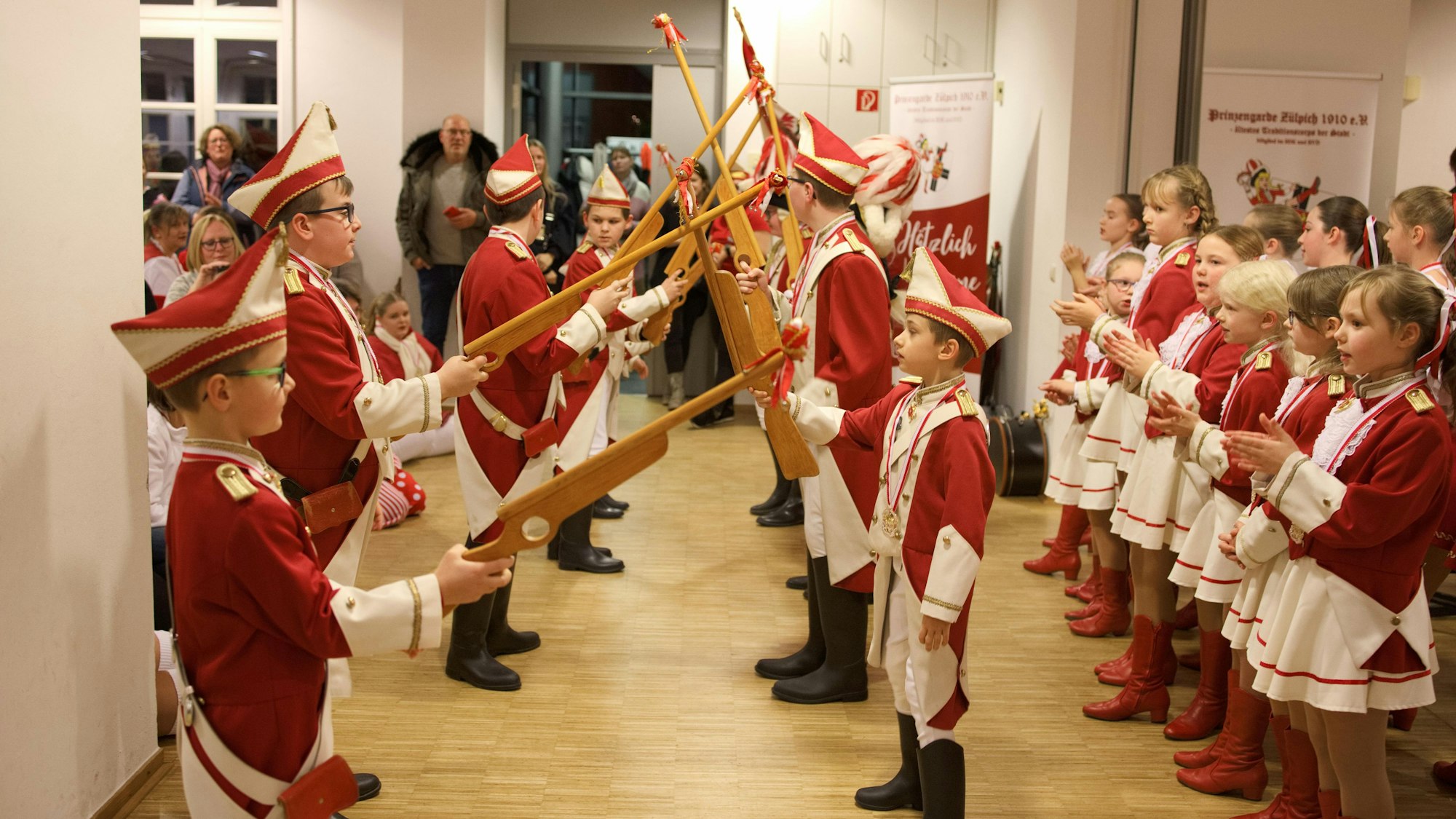 Die Jungen und Mädchen der Kinder- und Jugendtanzgruppe stehen in rot-weißen Uniformen Spalier.