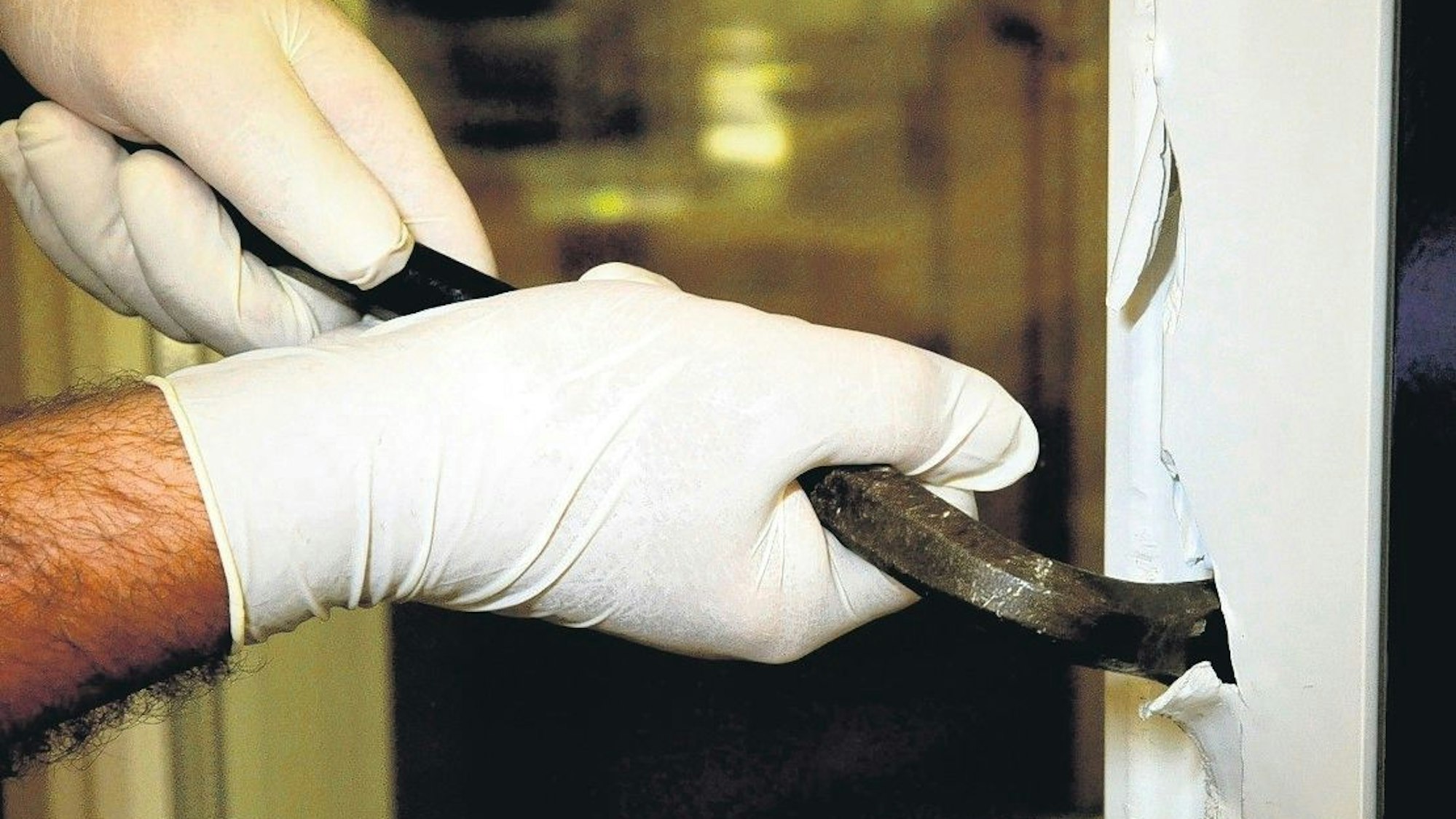 Ein Einbrecher hebelt eine Terrassentür auf. (Symbolbild)