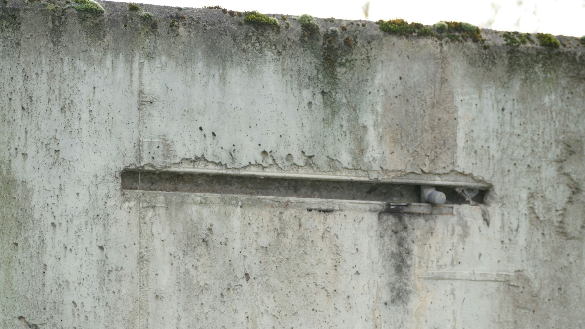 Ein Betonteil mit einer Einkerbung, in der eine Metallhalöterung zu erkennen ist.