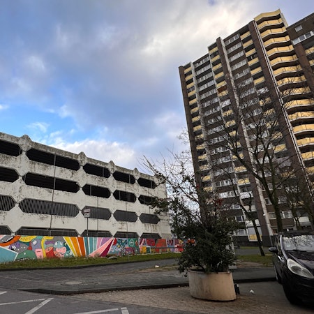 Blick auf ein viergeschossiges Beton-Parkhaus neben einem Hochhaus