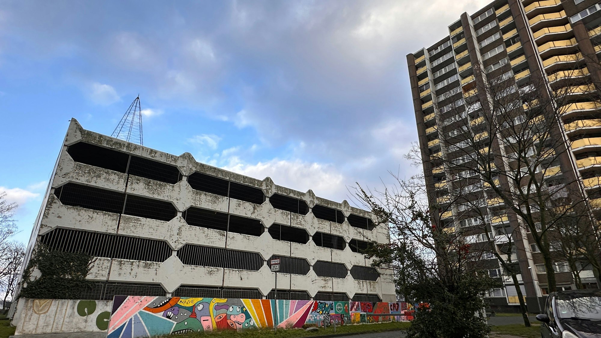 Blick auf ein viergeschossiges Beton-Parkhaus neben einem Hochhaus