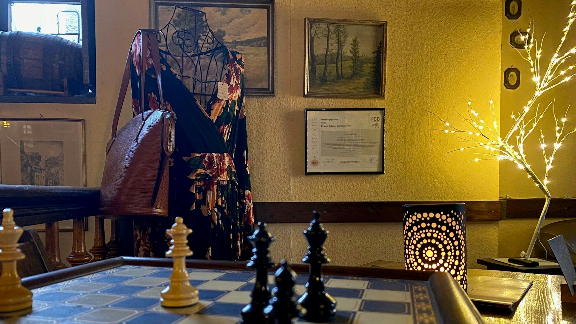Zu sehen ist das Lokal mit einem Schachbrett und einem ausgestellten Damenkleid.