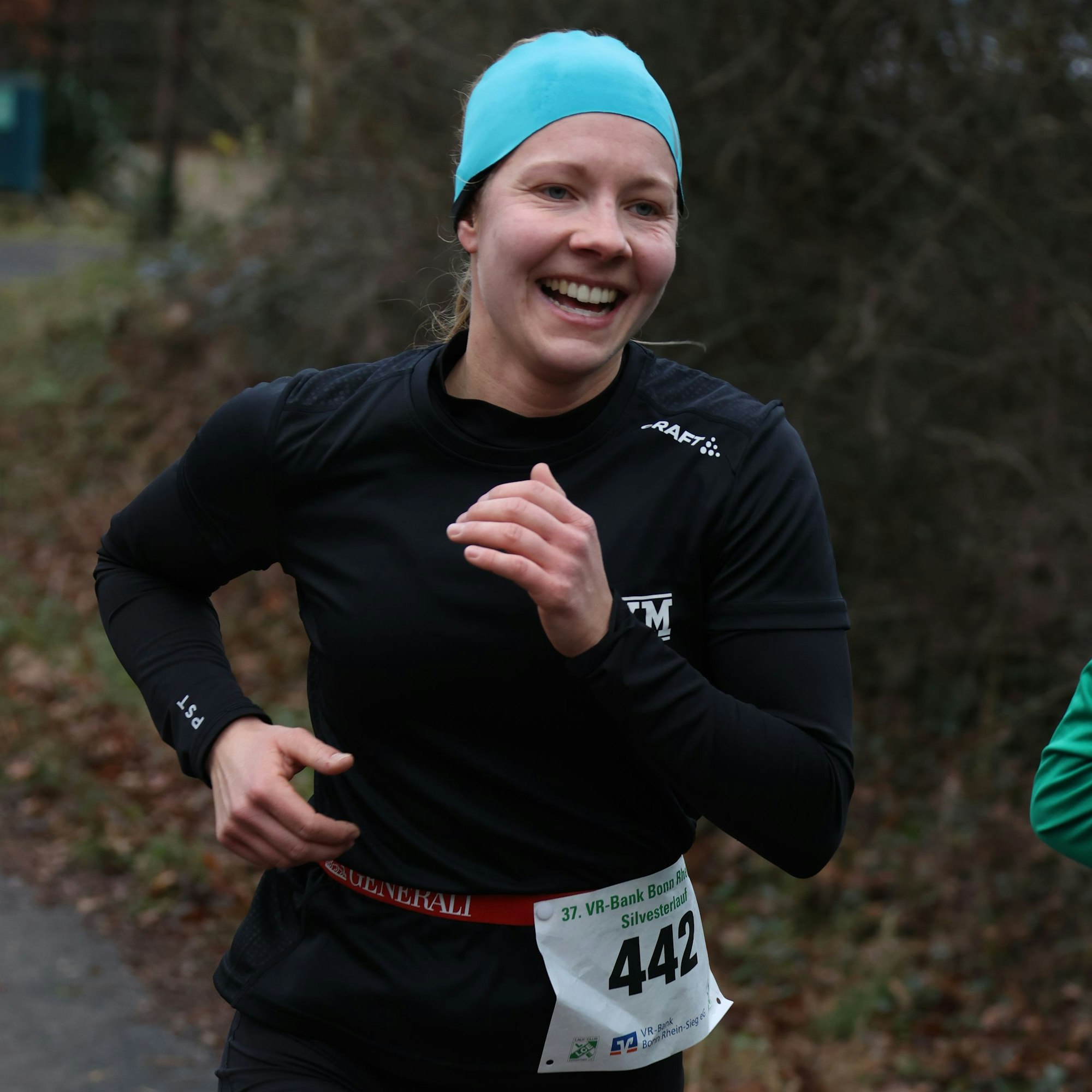 Nina Koep läuft mit türkisfarbener Mütze beim Silvesterlauf an der Steinbachtalsperre.