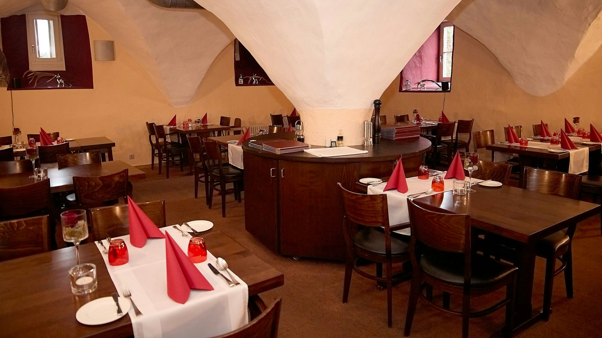 Im Gewölbe des Schlosses in Schleiden sind die Tische des Restaurants mit weißen Tischdecken und roten Servietten eingedeckt.