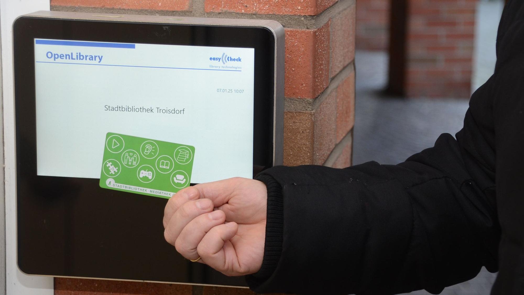 Eine Hand hält eine grüne Chipkarte vor ein Lesegerät.