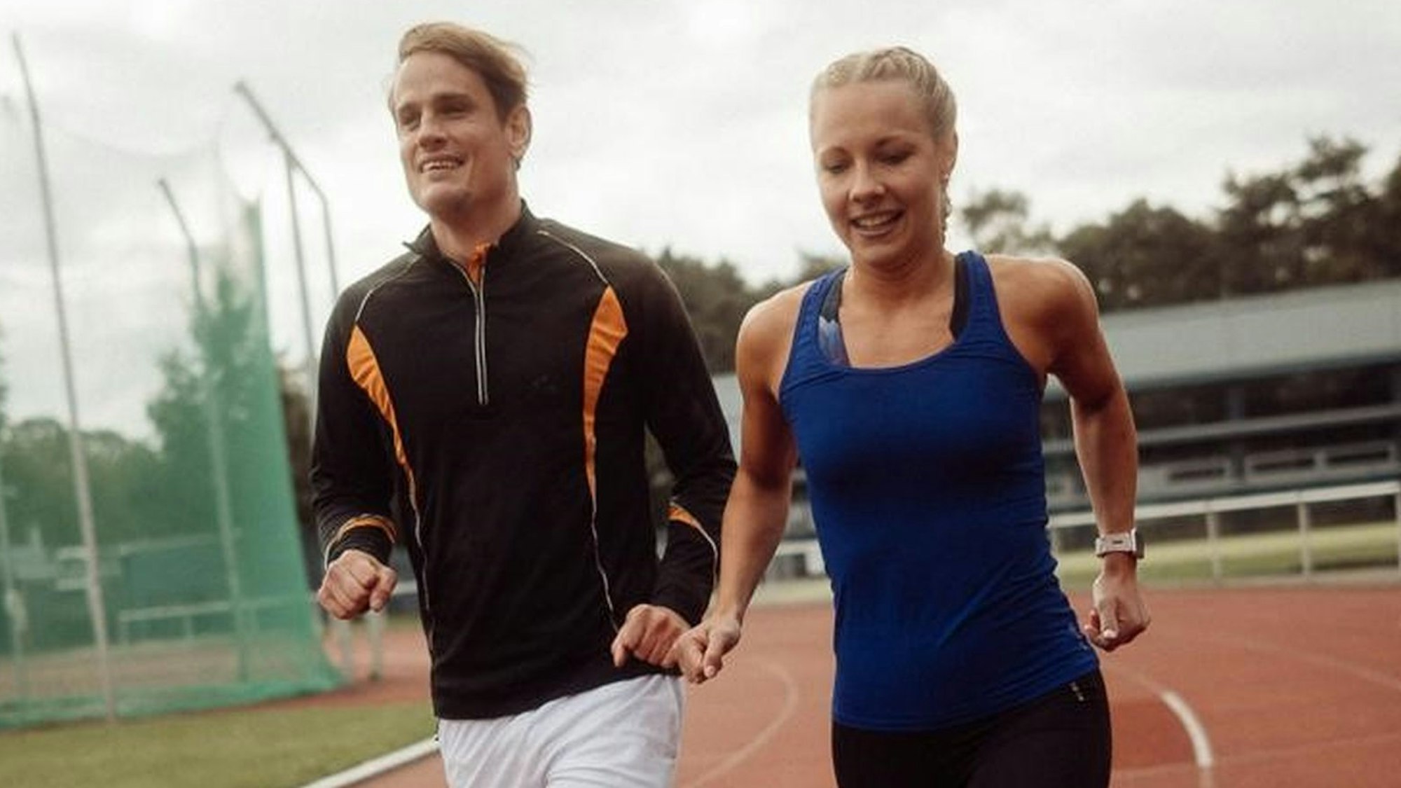 Nina Koep und der blinde Taime Kuttig laufen Faust an Faust über eine Tartanbahn.