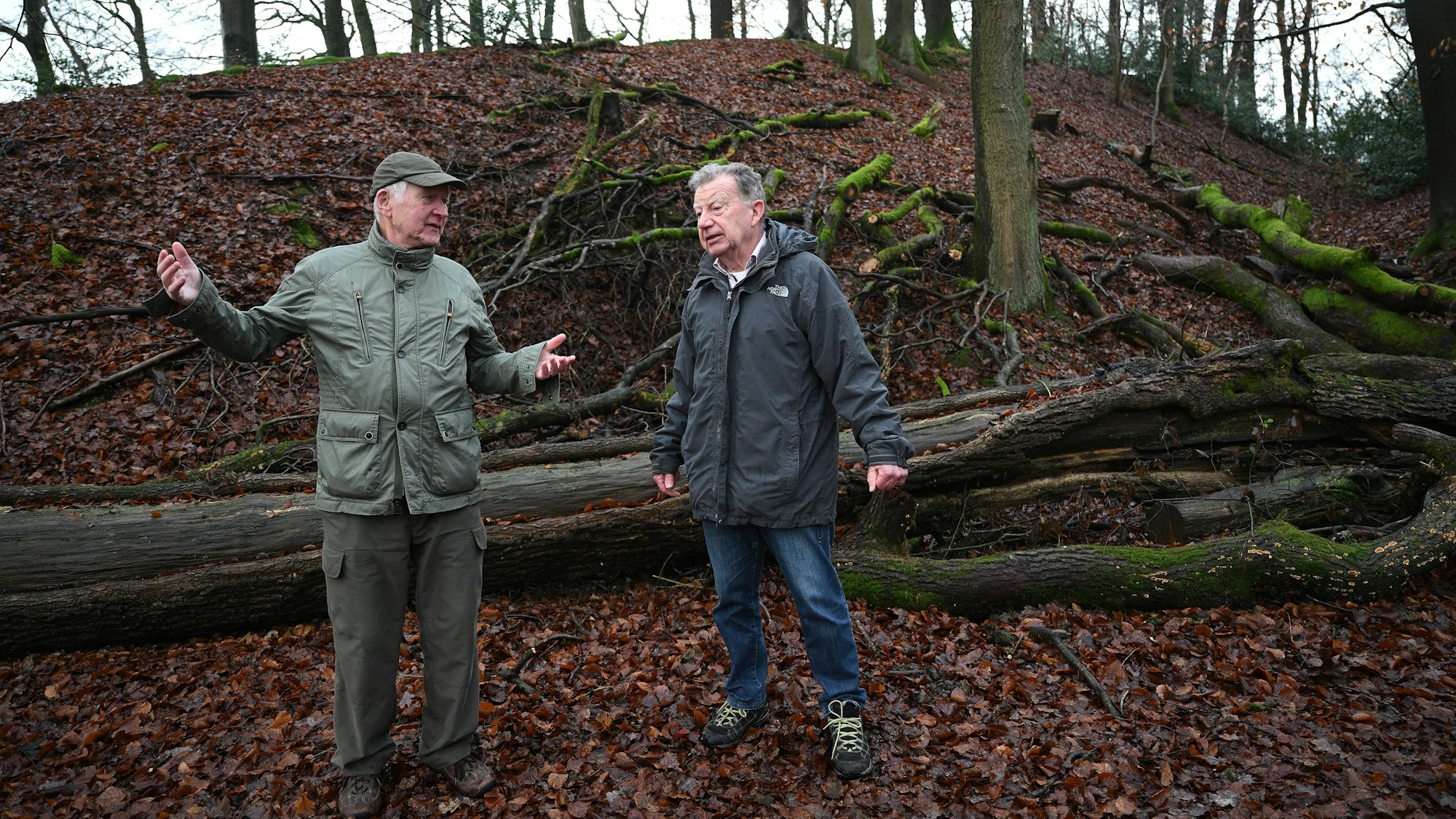 Zwei ältere Männer stehen an einem Abhang in einem bergischen Buchenwald.