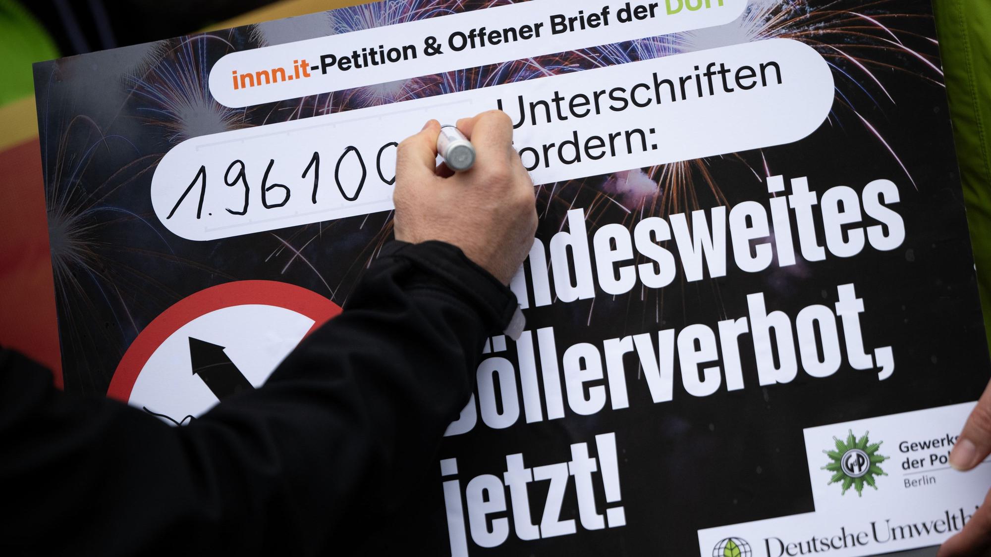 Eine Hand unterschreibt auf einem Plakat zum Böllerverbot.