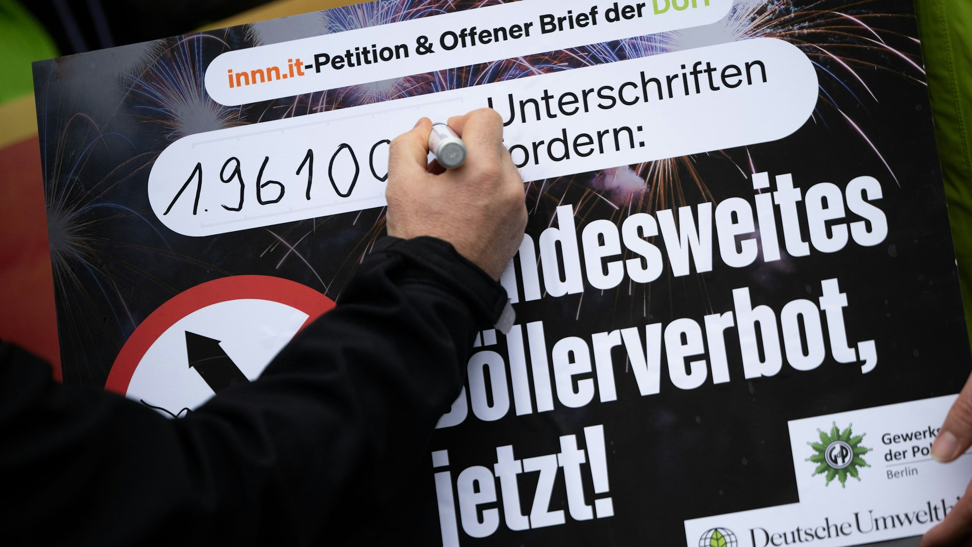 Eine Hand unterschreibt auf einem Plakat zum Böllerverbot.