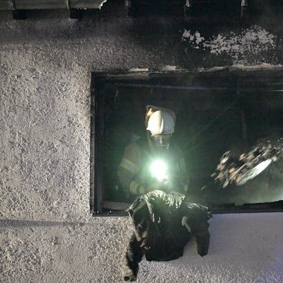 Ein Feuerwehrmann wirft eine Jacke aus dem Fenster einer Brandwohnung in Bergisch Glabach-Voislöhe.