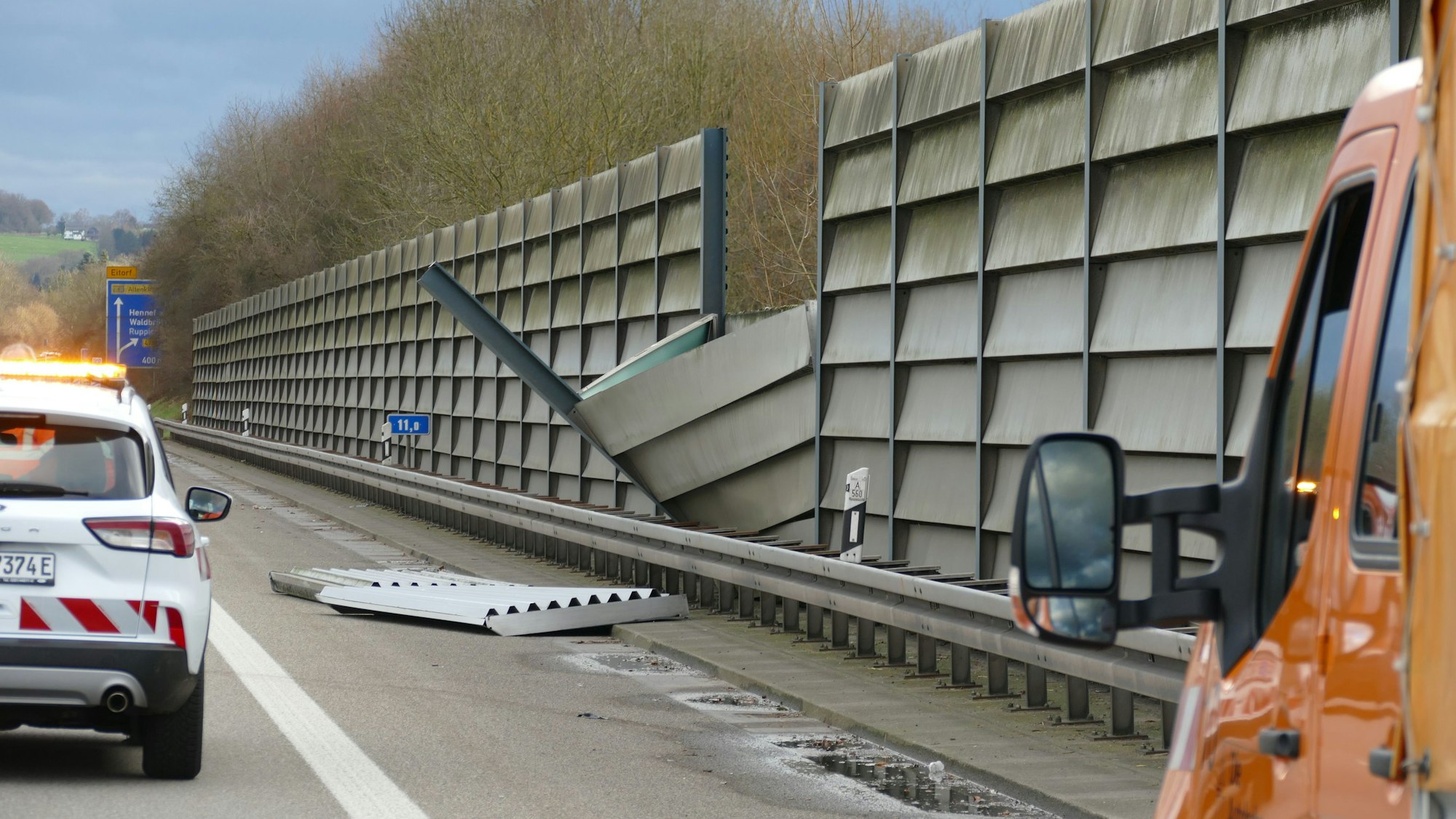 Teile einer umgestürzten Lärmschutzwand neben einer Autobahn.