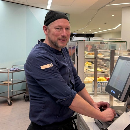 Ein Mann steht in einer Kantine an der Kasse