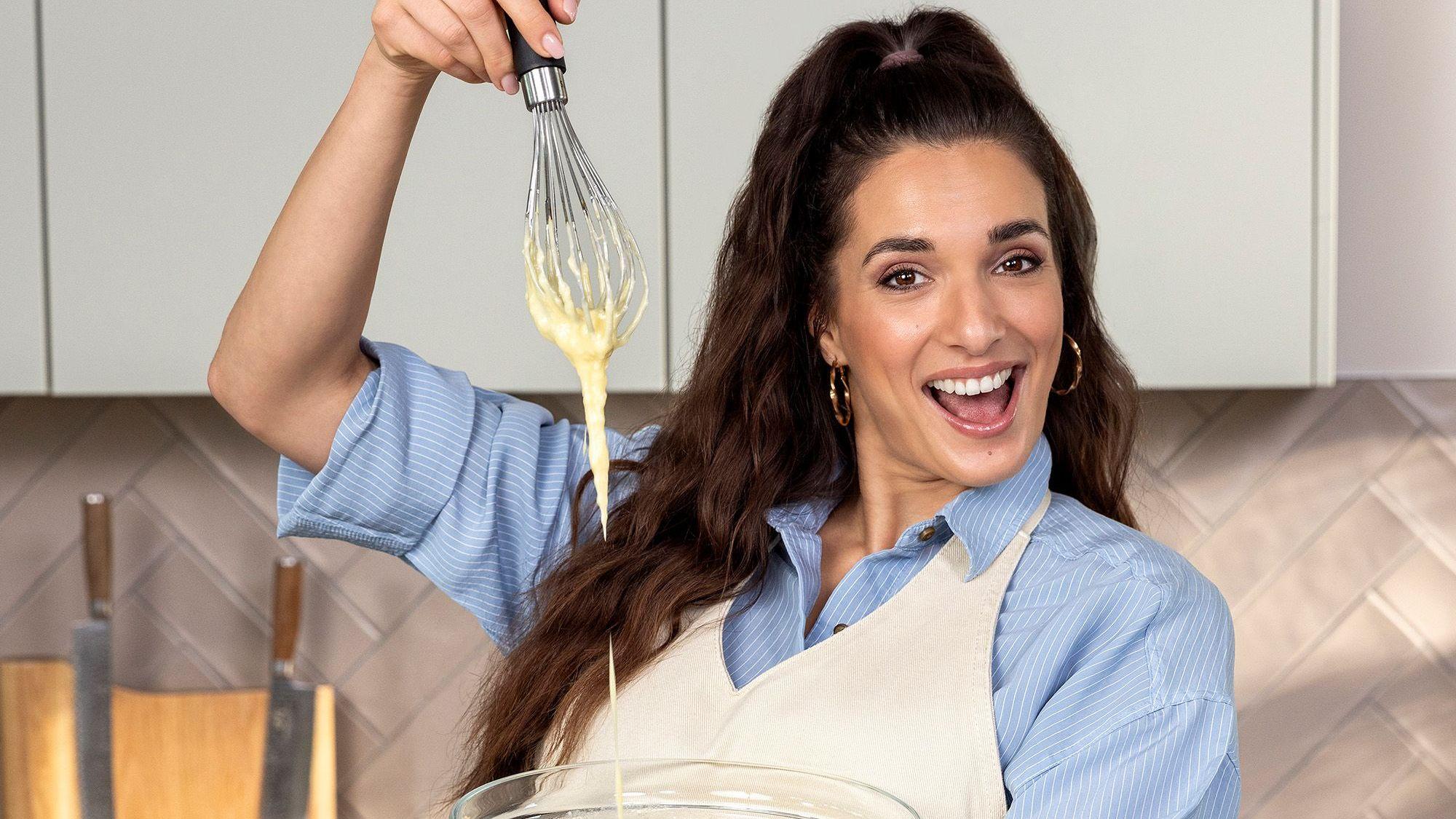 Sally Özcan steht mit einem Schneebesen in der Hand in der Küche.