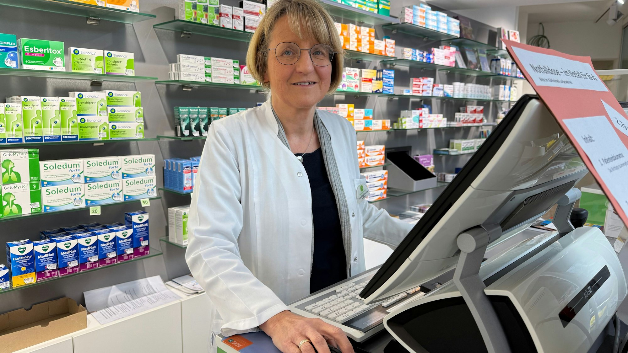 Eine Apothekerin hinter ihrer Kasse.