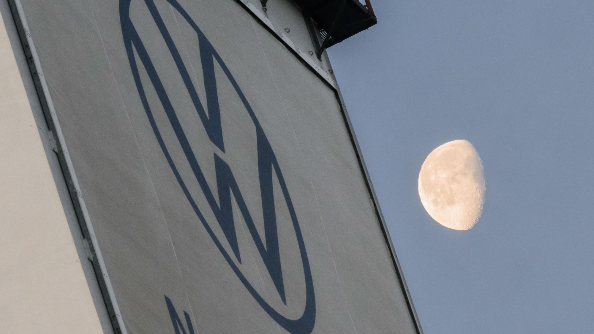 VW verschärft seinen Sparkurs. Das VW-Logo ist an einer Wand zu sehen, im Hintergrund sieht man den Mond.