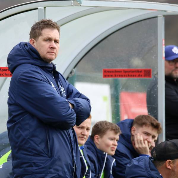 Trainer Kevin Greuel steht mit verschränkten Armen vor der Ersatzbank.