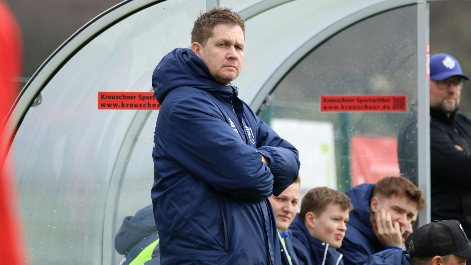 Trainer Kevin Greuel steht mit verschränkten Armen vor der Ersatzbank.