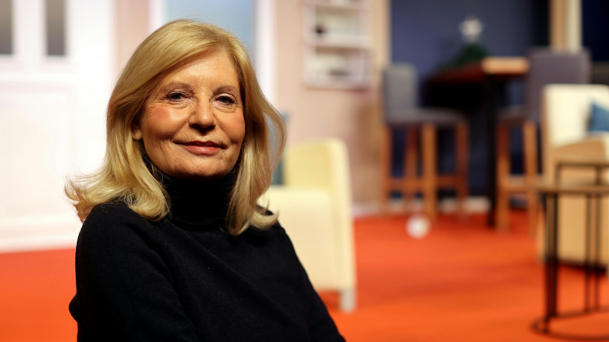 Sabine Postel sitzt auf einem Stuhl im Theater am Dom.