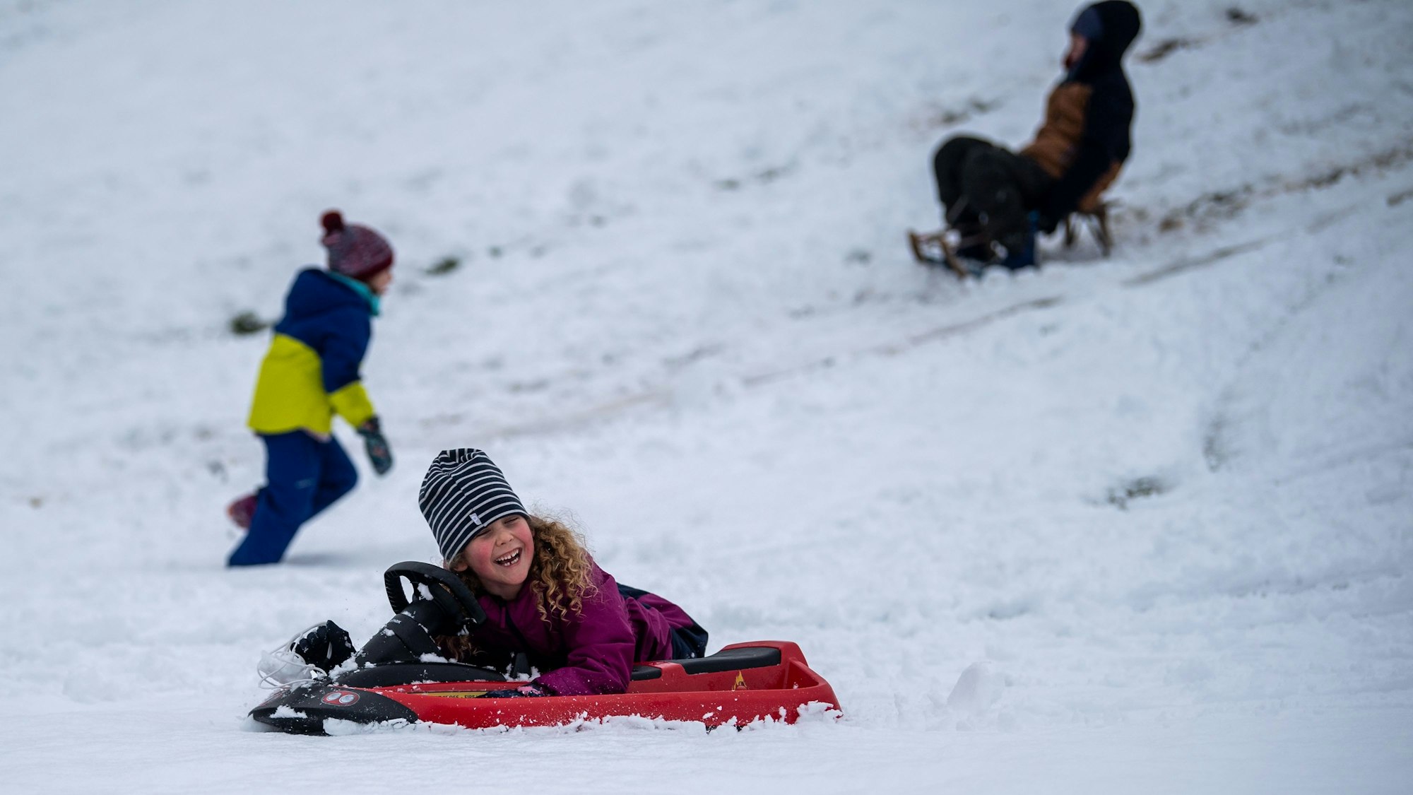 Das Bild zeigt ein Mädchen, das sich über den Schnee freut.