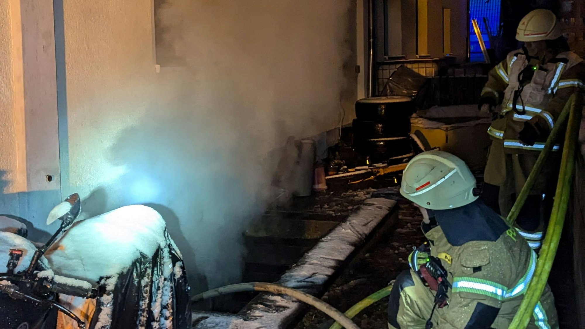 Das Bild zeigt Feuerwehrmänner vor einem rauchenden Kellerschacht.