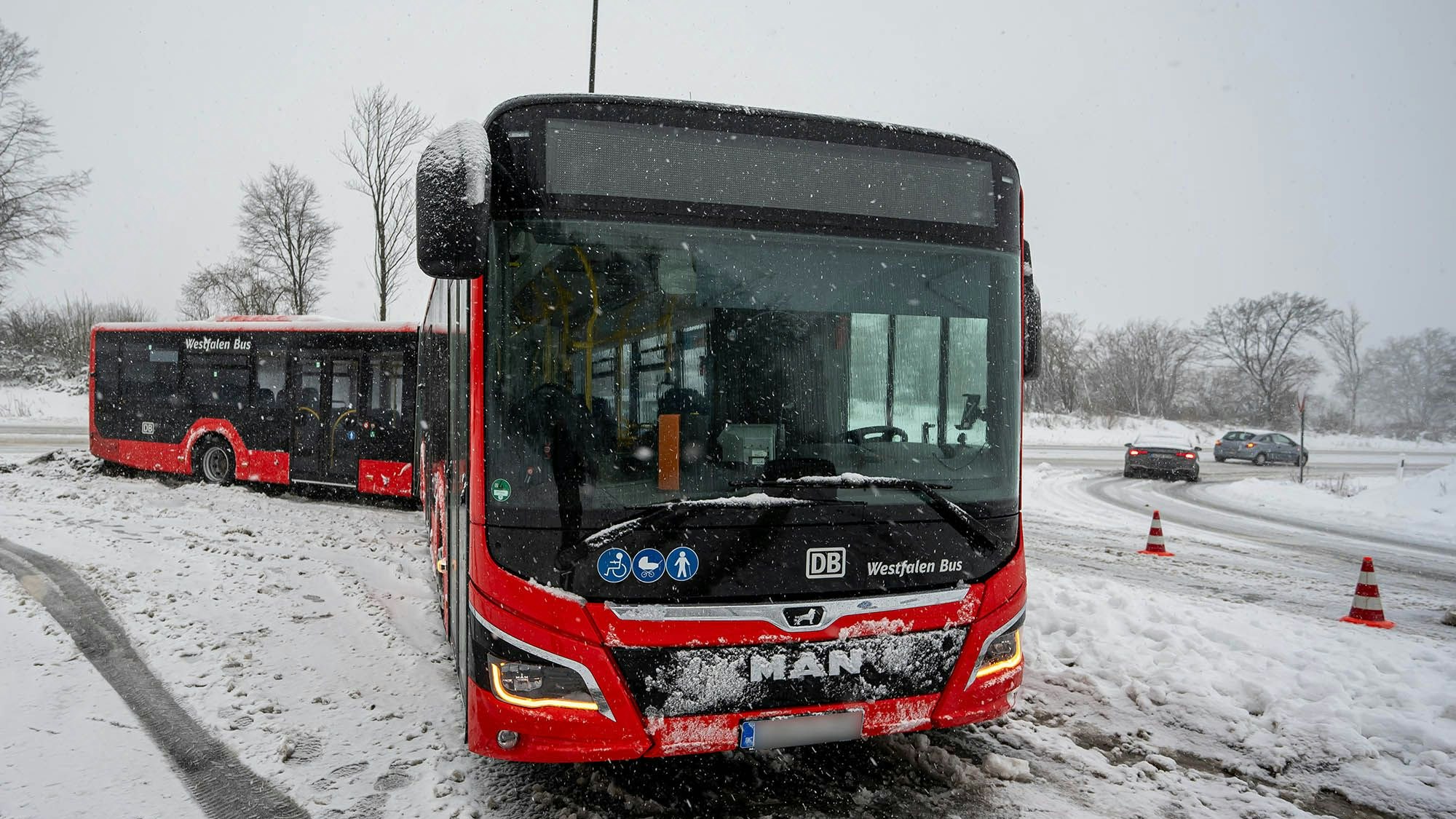 Ein Linien-Gelenkbus ist im Schnee auf einem Kreisverkehr liegengeblieben.